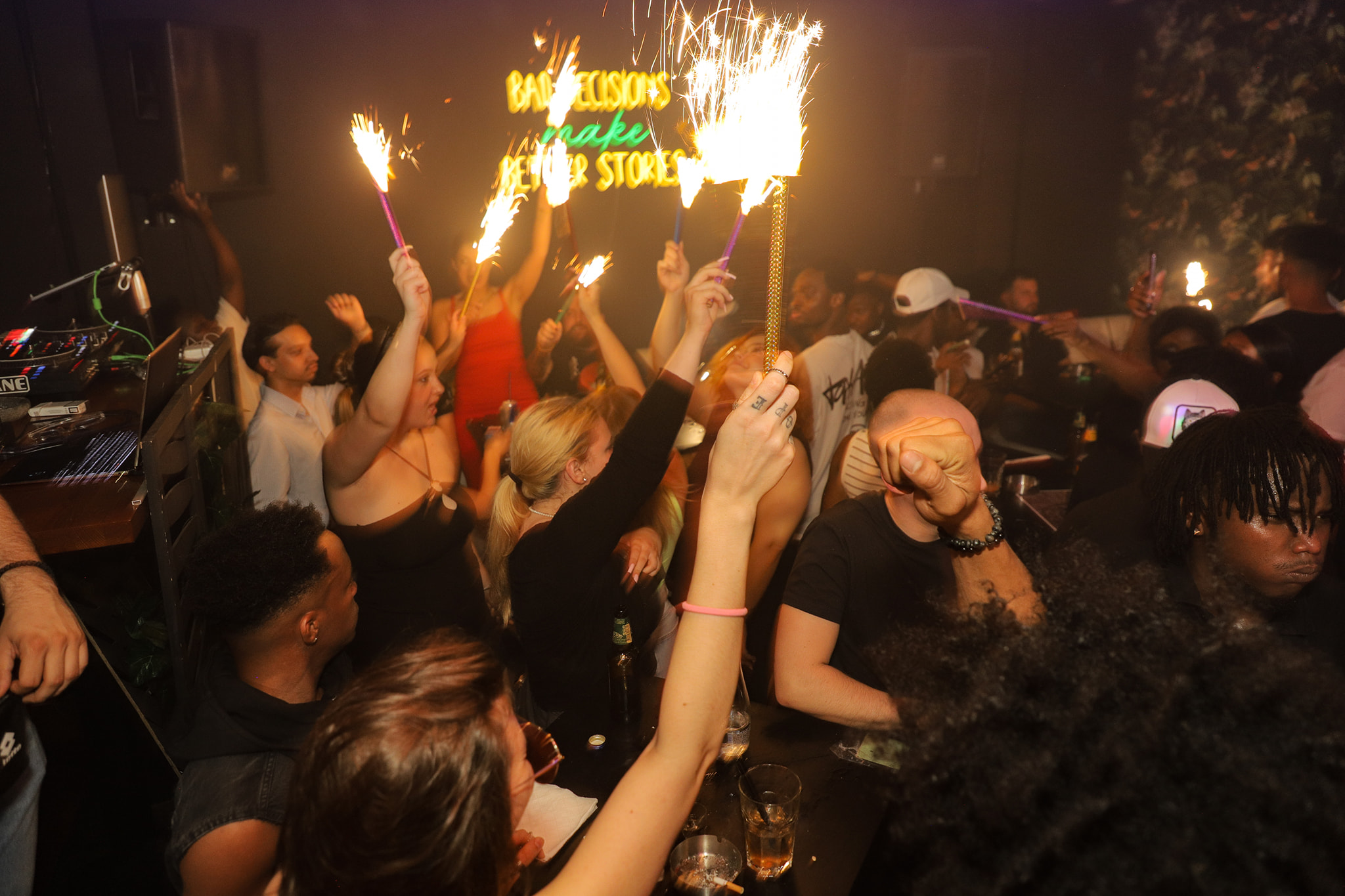 A crowd of people celebrating with sparklers in a dark club.