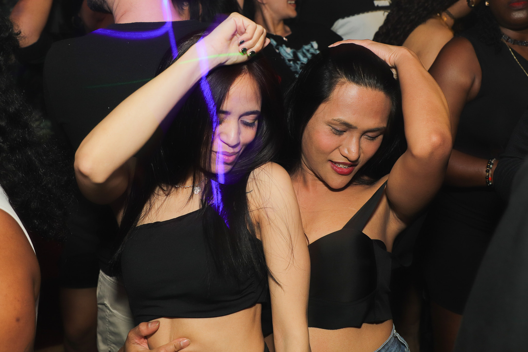 Two women dancing together, lost in the music on the dance floor.