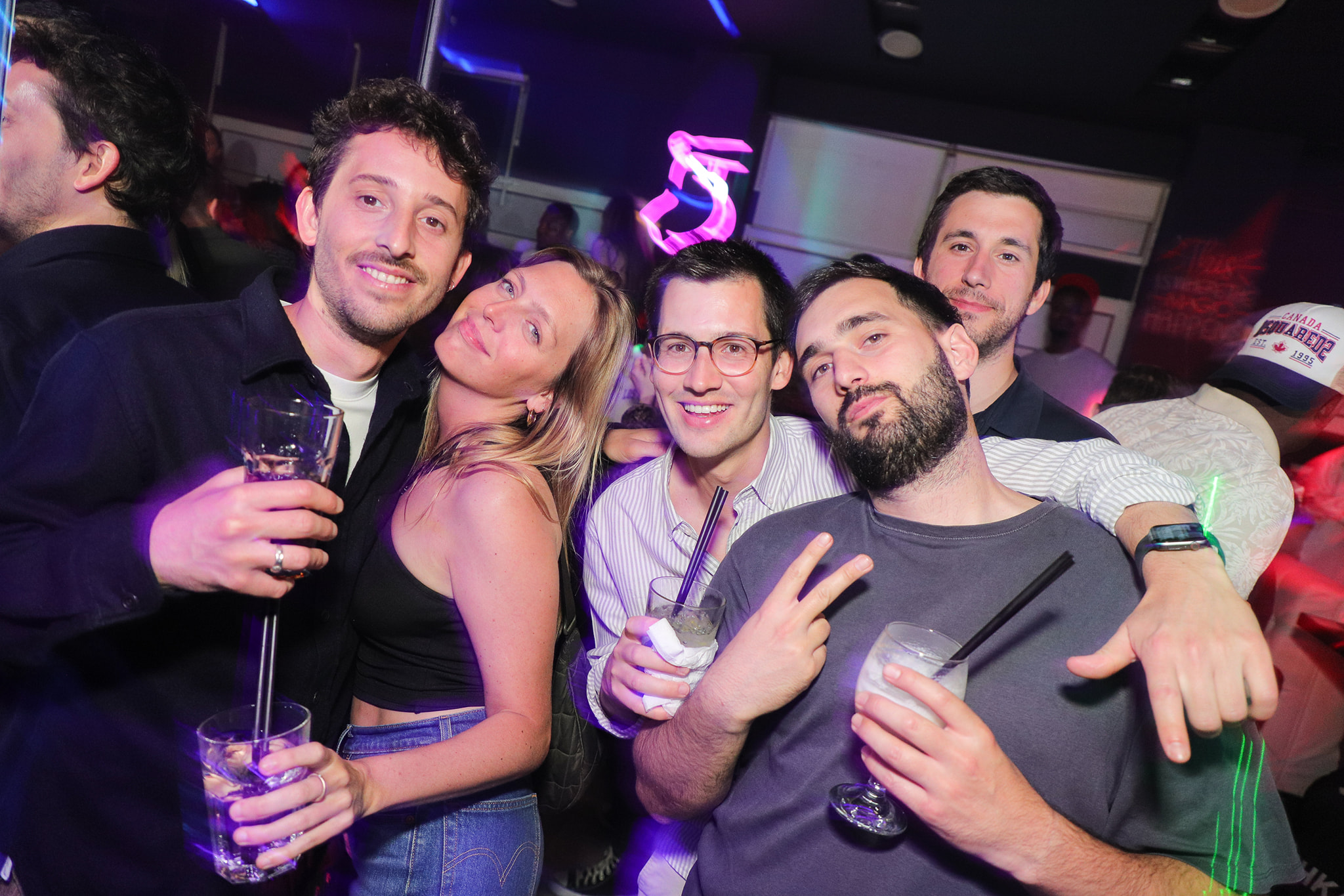 A group of friends smiling and posing for a photo with their drinks.